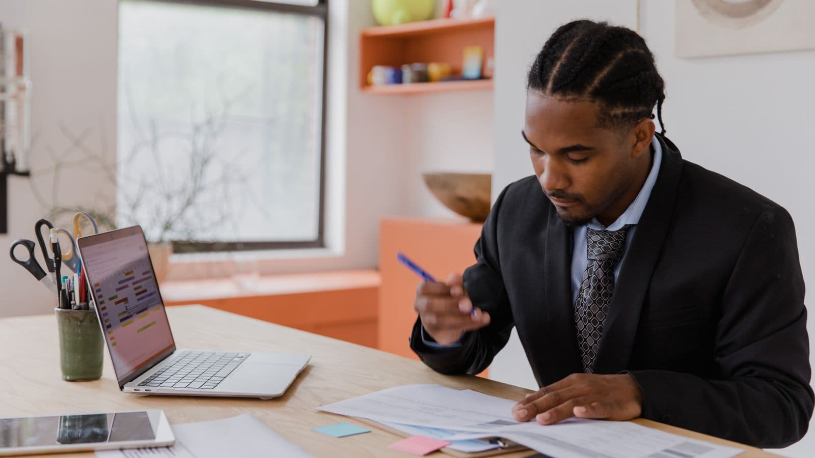 A businessman reviewing documents at a desk in a modern office, representing expense report software for small businesses