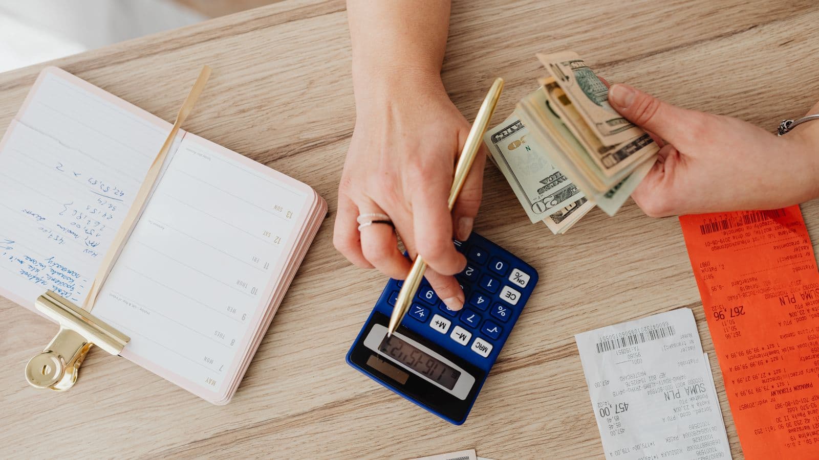 A person using a calculator and notebook to work out a business trip's per diem total