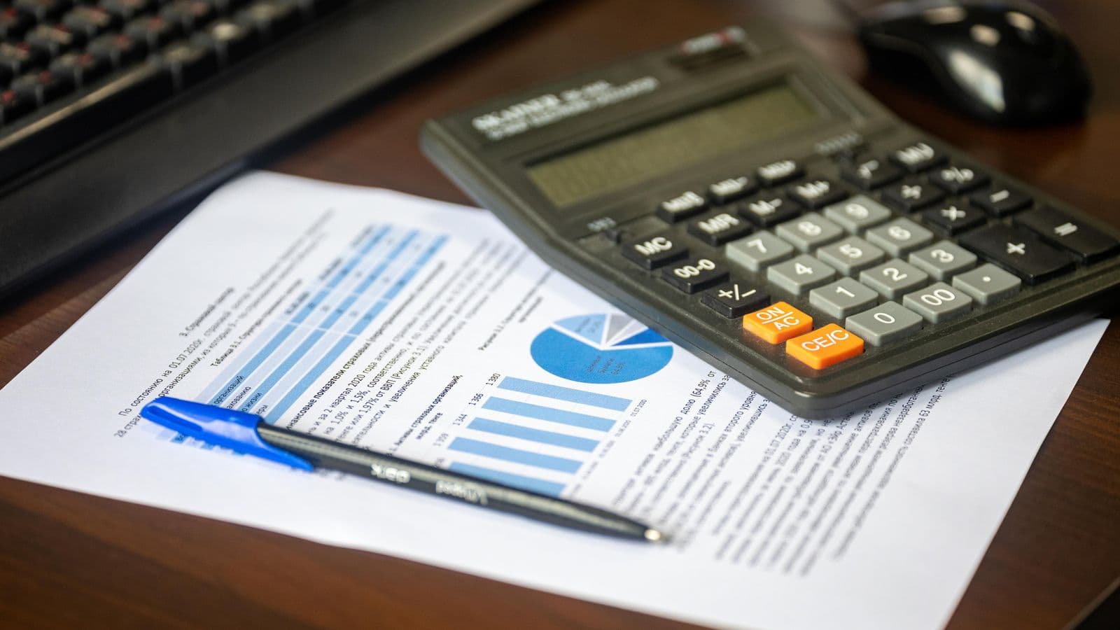 A desk with a calculator and financial report, representing IRS mileage reimbursement rules for employers