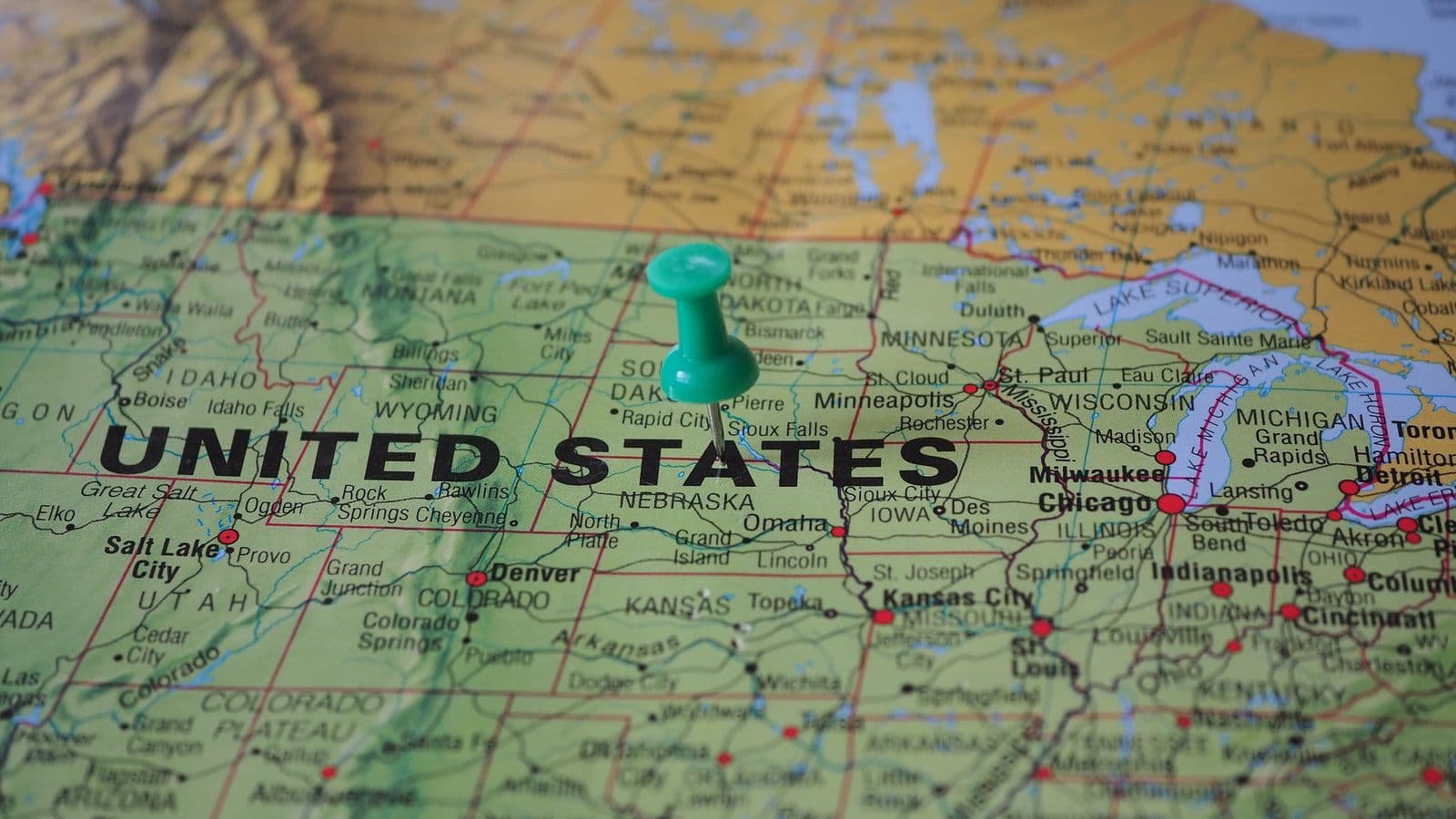A US map overlaid with pins marking cities alongside a calculator and hotel receipt, representing FY2026 per diem rate lookups