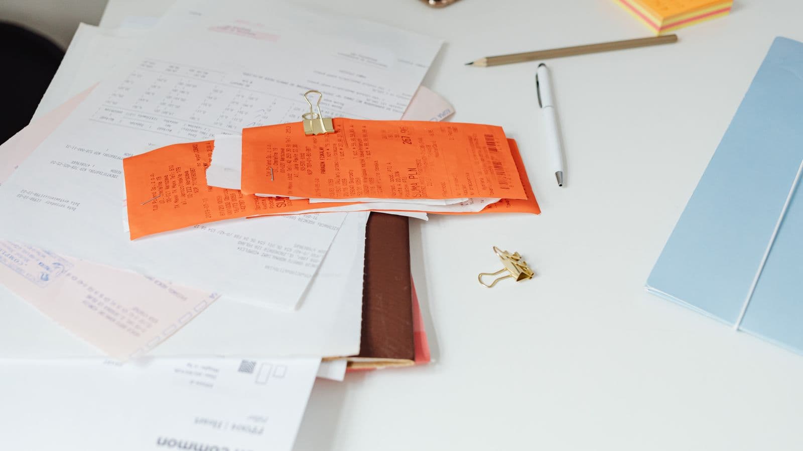 A pile of paper receipts and invoices on a desk, representing actual-expense reimbursement versus flat per diem